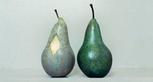 Two sculptures of pears against a blank background.