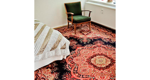 Blue and red oriental rug with a green chair sitting on it.