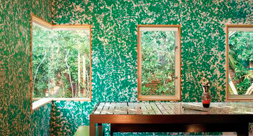 Windows of flowers on a green patterned wall.