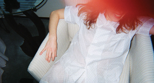 Woman in white pajamas sitting on a chair.