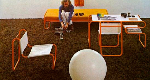 Man in a room with orange, white, and yellow furniture.