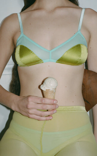 A model wearing the Beatrice Bralette in green and blue silk, holding an ice cream cone.