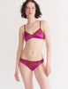 a model in the beatrice bralette and aaron panty in amaranth magenta and red