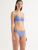 a three-quarters image of a model in the tamara bralette and tris panty in serene blue