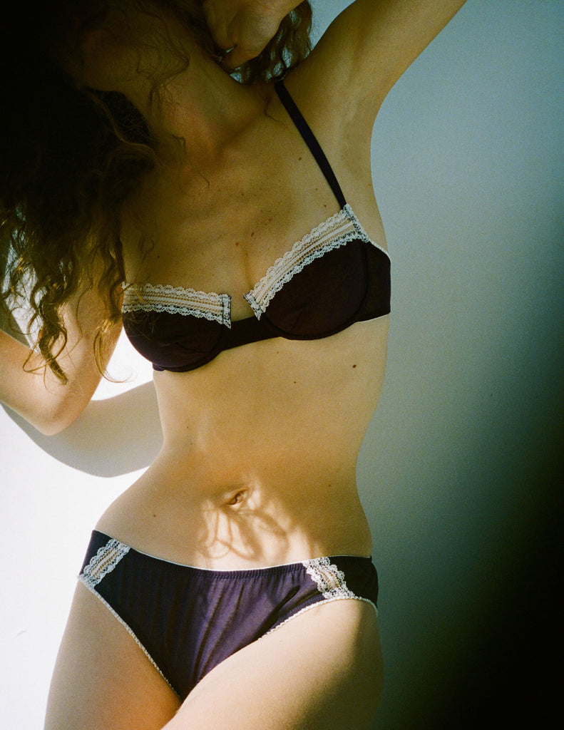 a model wearing the chloe bra and sonja panty in dark purple cotton 