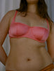 a model wearing the gita underwire bra in bright pink.