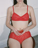 a model holding chili peppers wearing the tamara bralette and imogen hipter in red lace